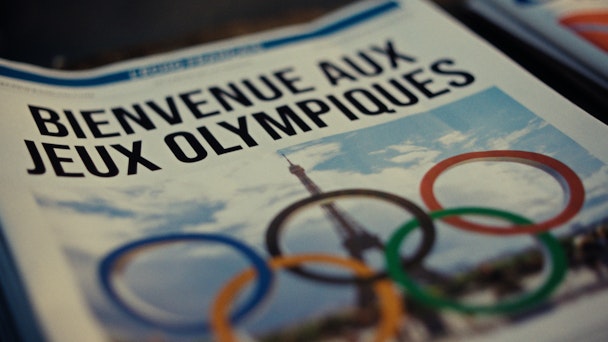 The front page of a newspaper reads 'Welcome to the Olympics' in French