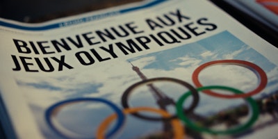 The front page of a newspaper reads 'Welcome to the Olympics' in French