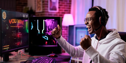 Man fist pumping in front of gaming screen with headphones