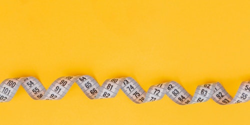 A twisted tape measure against a yellow background