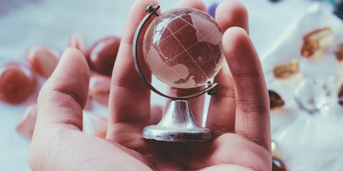 A tiny glass globe, held in the palm of a hand