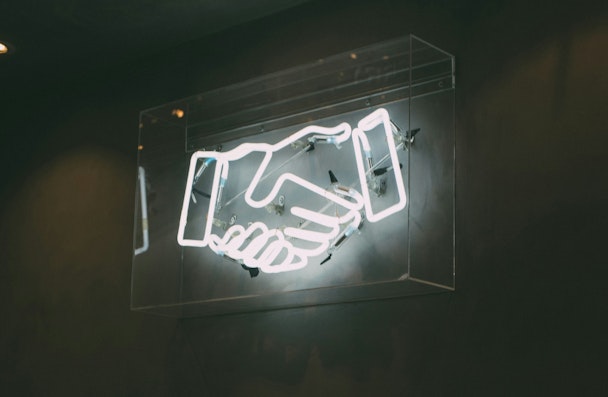 A neon sign of shaking hands