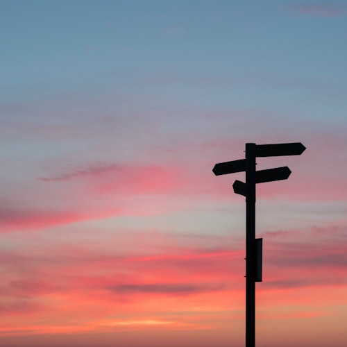 A signpost against a gradient sunset sky