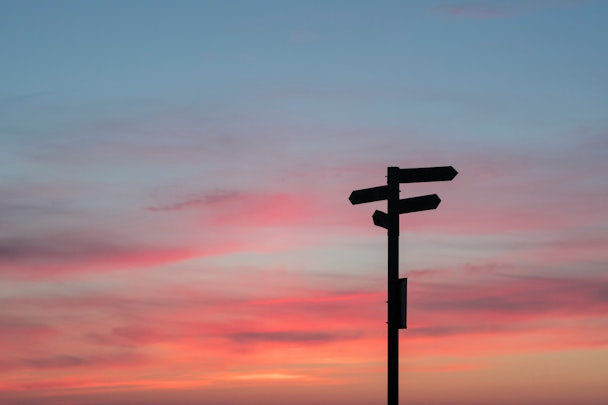 A signpost against a gradient sunset sky