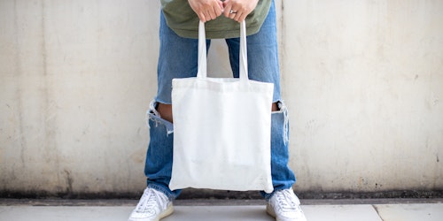 A person struggling to lift a heavy canvas bag