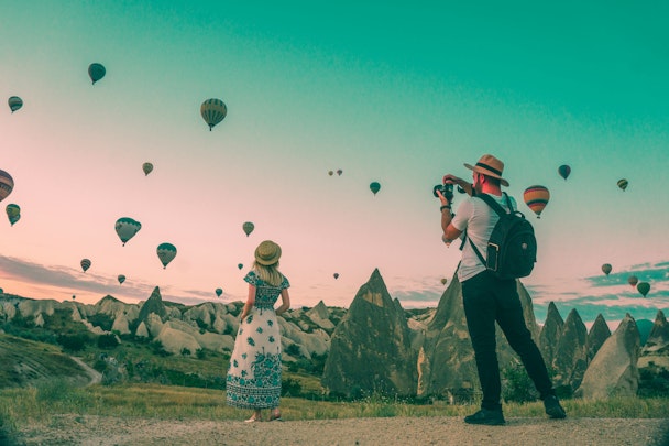 Two travel influencers amid a field of hot-air balloons