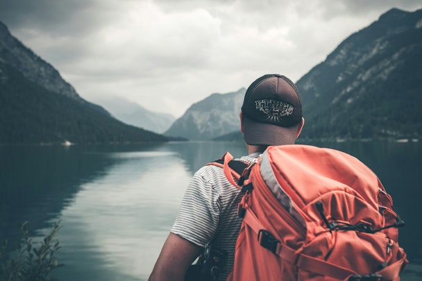 A man with a backpack looking out over a lake