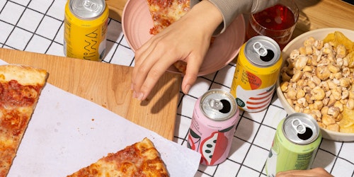 Three hands pick at different snacks laid out on a table