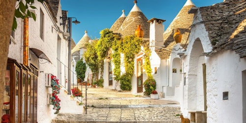 Travel image of a sunlit stone street with white villas