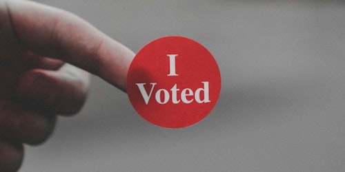 A sticker reading 'I voted' on the end of someone's finger 