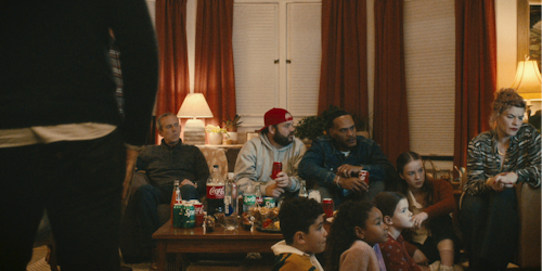 People watching TV with multiple The Coca-Cola Company products on the table 