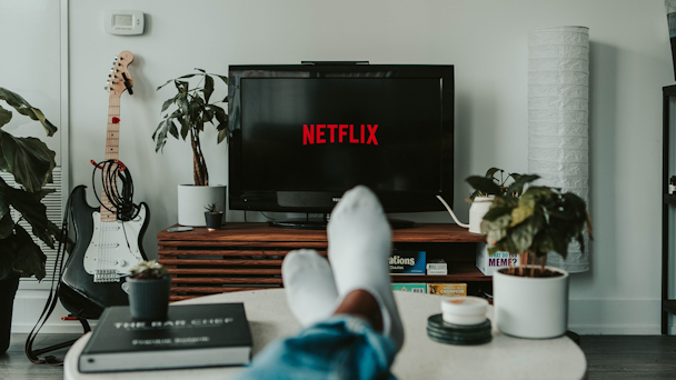 Netflix on TV screen with man's feet in foreground