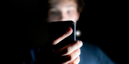 Guy holding cell phone in dark room