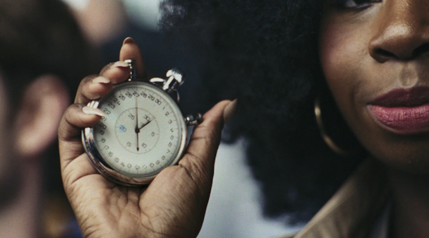 ‘Time’ is portrayed as a spectator holding a ticking stopwatch up to sprinter Emmanuel Oyinbo-Coker