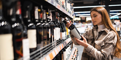 Young woman looking at wine bottle 